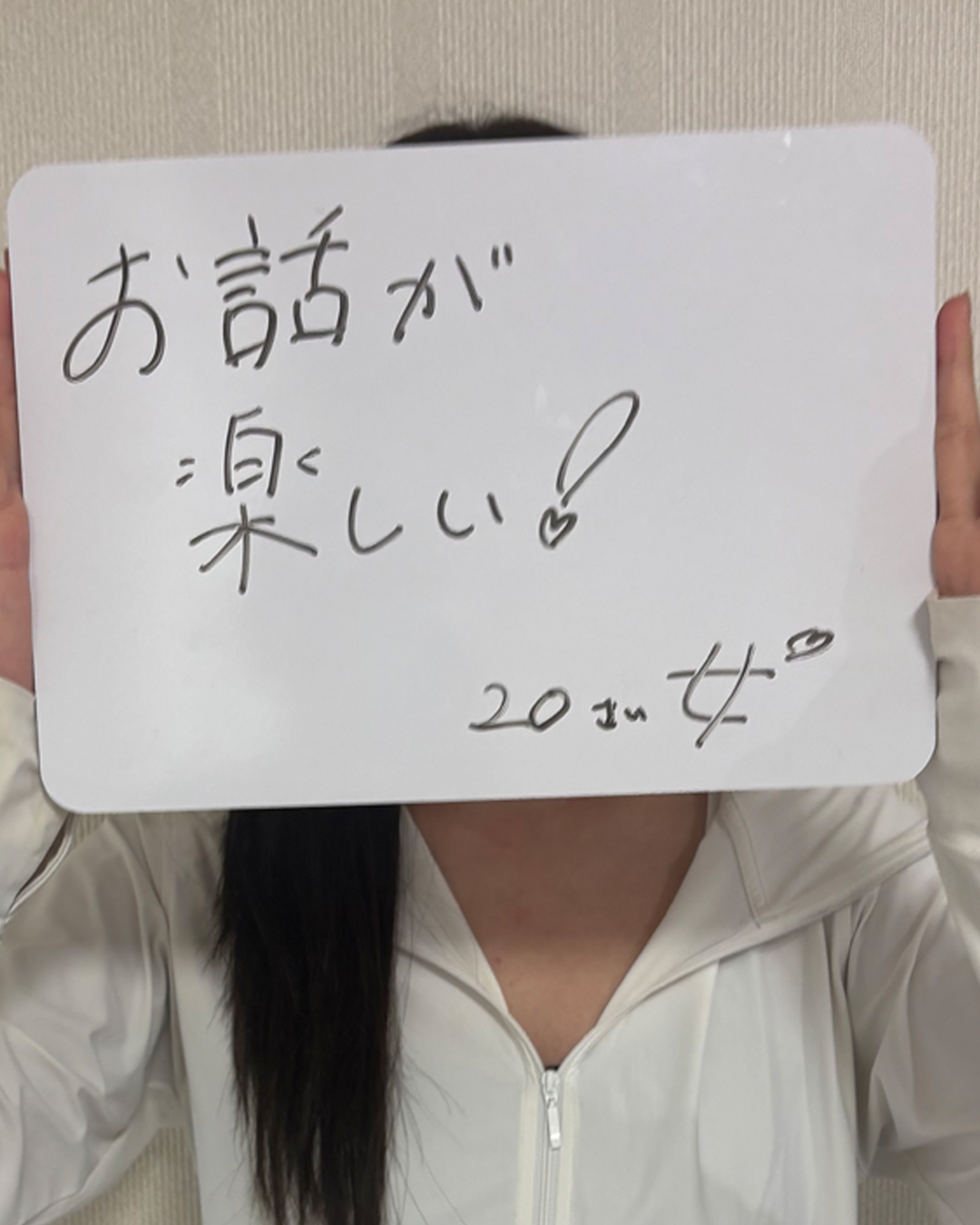 「お話が楽しい！」という感想を書いたホワイトボードを持つ20代女性のお客様の口コミ写真。